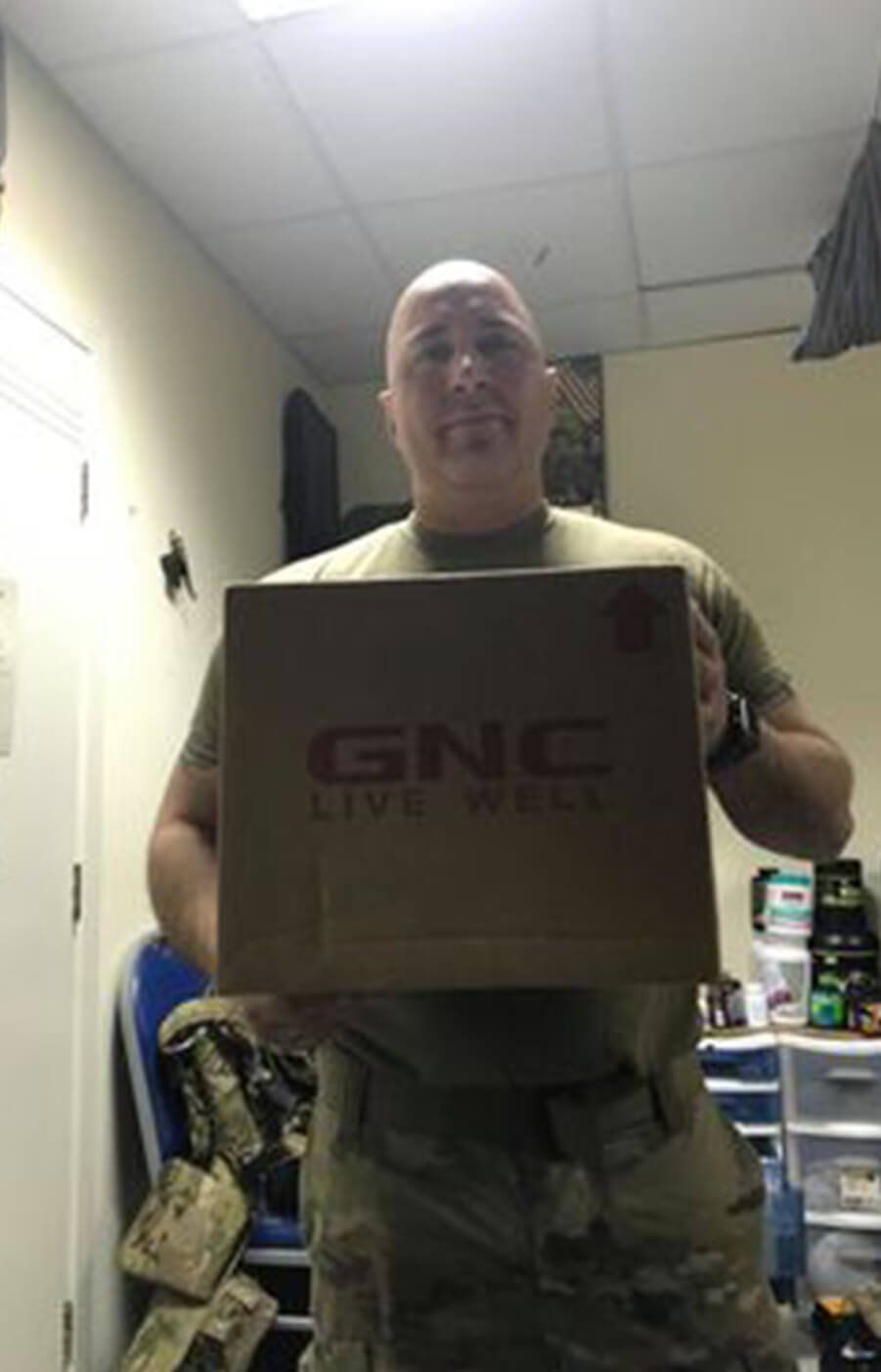 Troop holding care package and sign